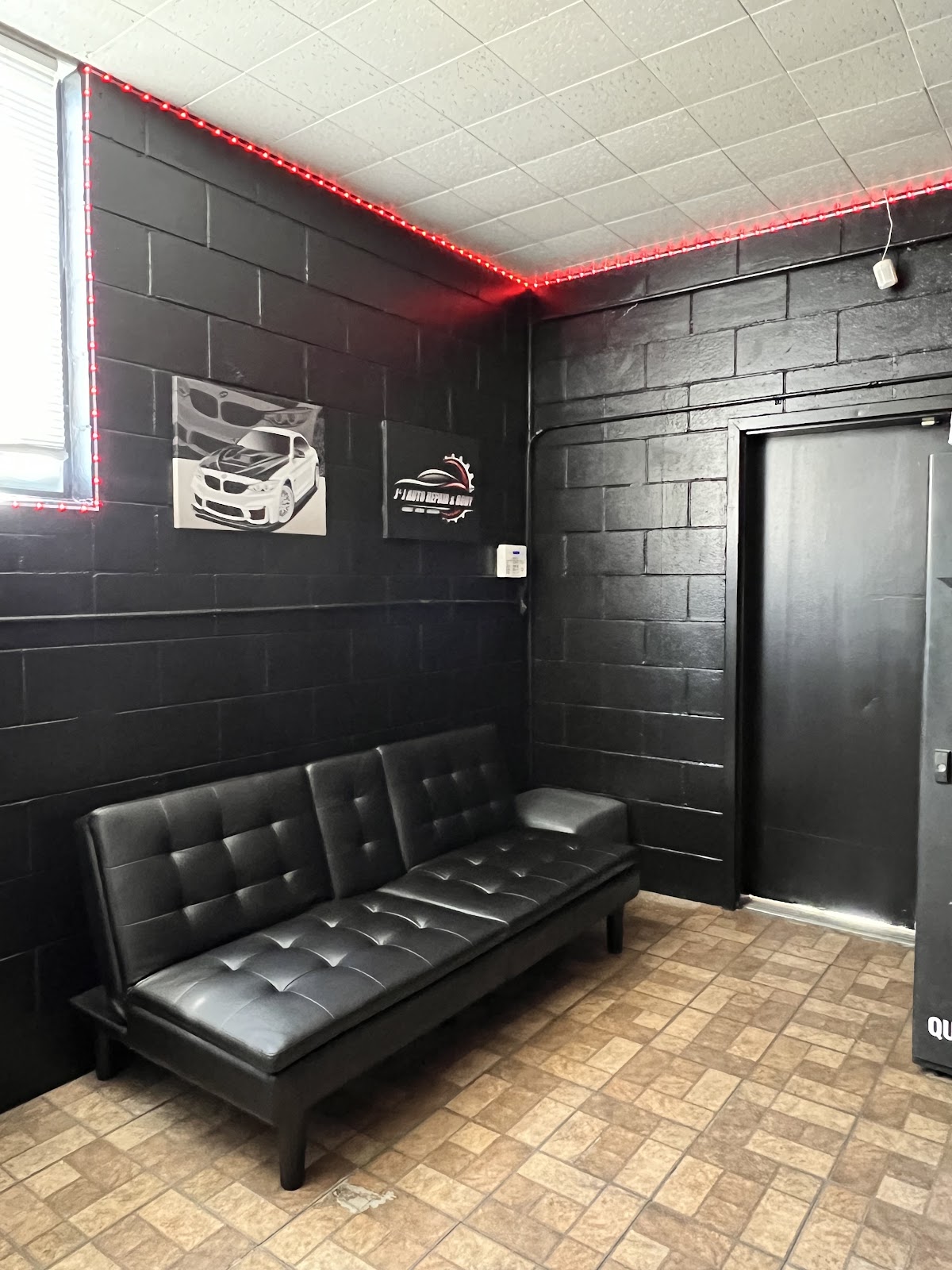 The J and J customer waiting room, black painted walls with a red LED strip and the shop logo plaque