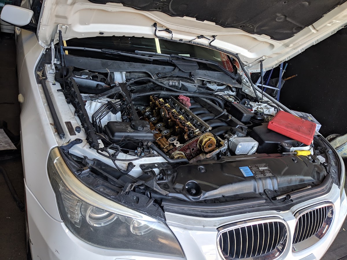 White BMW E60 with the valve cover off and the timing chain exposed